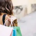 Shopper browsing affordable autumn clothing and accessories on a store shelf with visible price tags