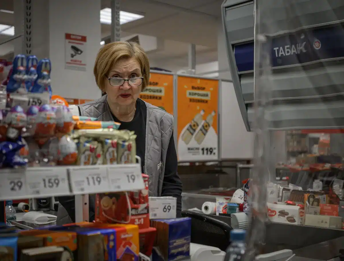 Supermarket staff member at checkout serving customers