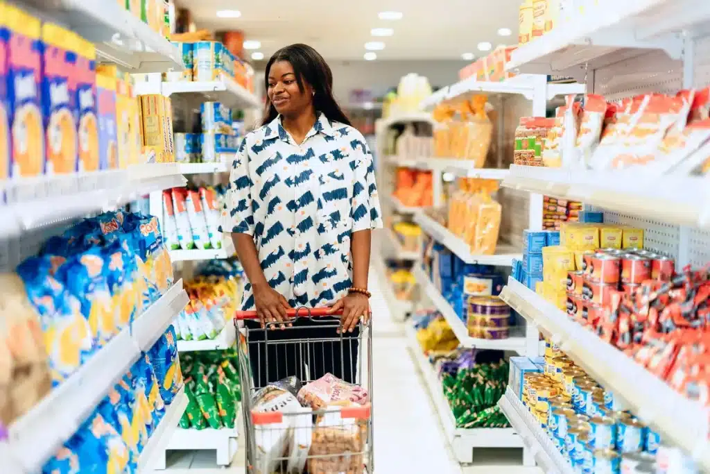 Shopper with basket in a modern discount supermarket aisle with affordable products