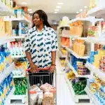 Shopper with basket in a modern discount supermarket aisle with affordable products