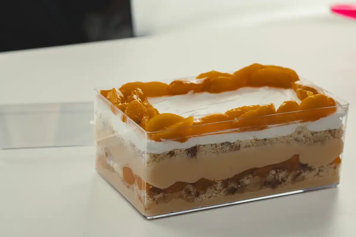 Stacked cheesecake bars separated by parchment in an airtight container ready for freezing