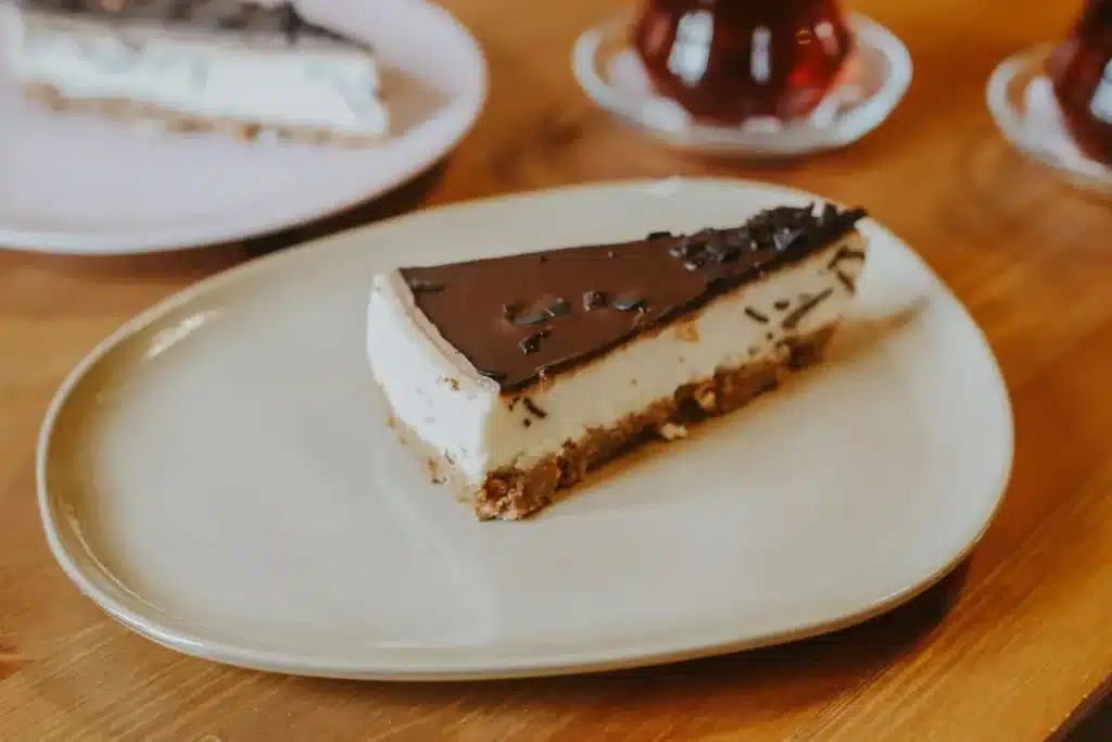 Golden-brown apple crisp cheesecake bar with layers of crust, cheesecake, apples, and oat topping