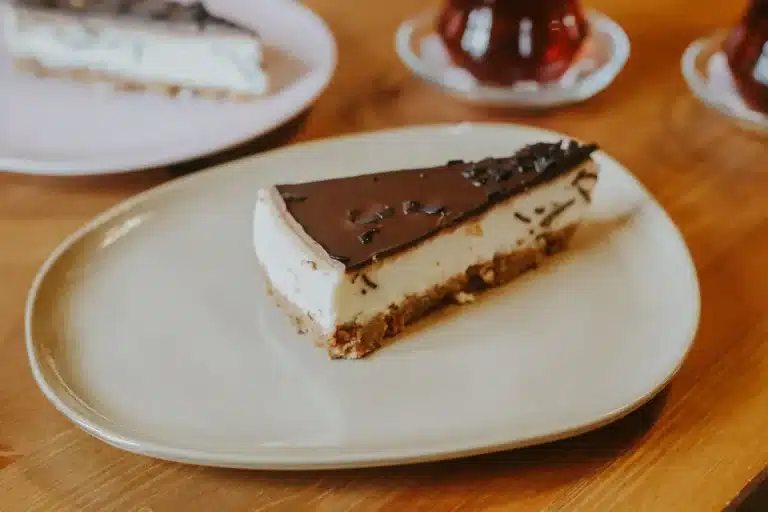 Golden-brown apple crisp cheesecake bar with layers of crust, cheesecake, apples, and oat topping