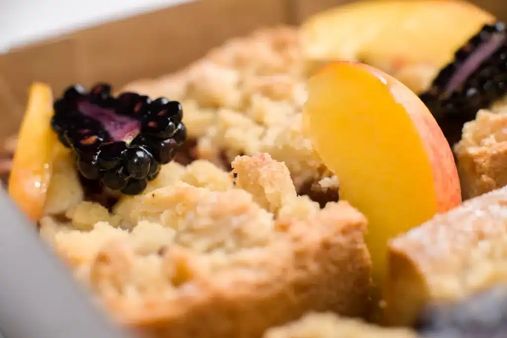 Golden-baked blackberry cobbler with berries visible through the crust, steam rising from a baking dish