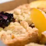 Golden-baked blackberry cobbler with berries visible through the crust, steam rising from a baking dish