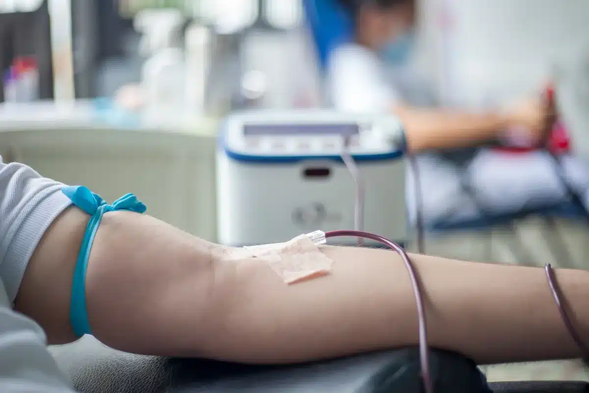 Healthcare worker collecting blood from a donor's arm during a donation procedure