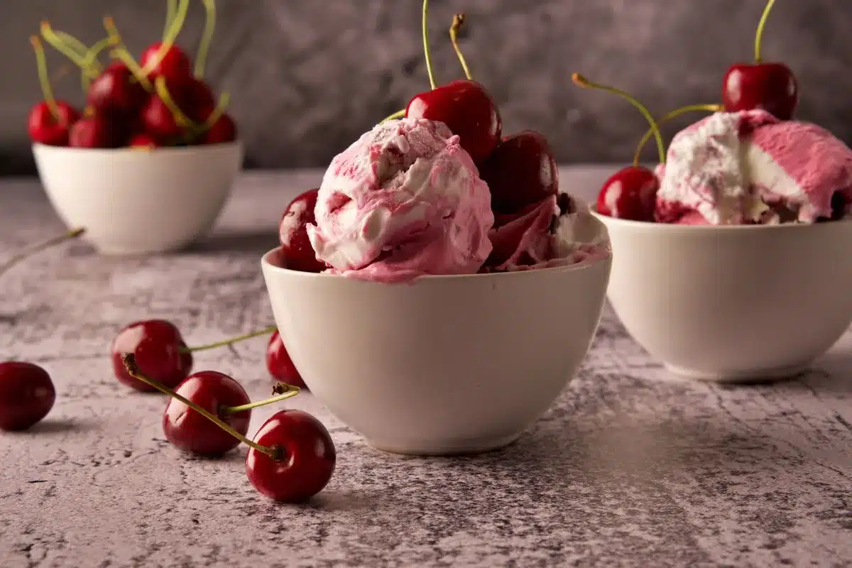 Warm cherry cobbler served in a bowl with vanilla ice cream melting on top