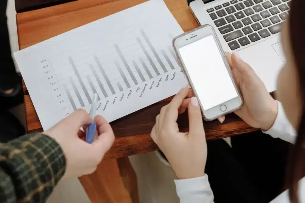 Person's hands holding a smartphone displaying a form on a desk with papers and tea nearby