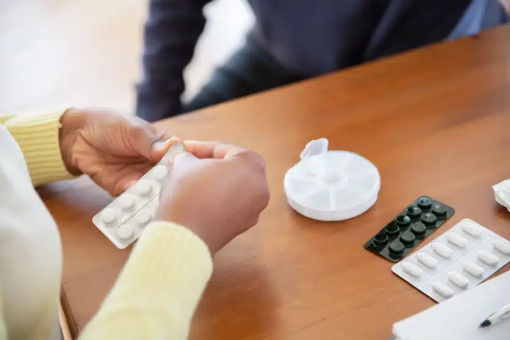 A hand holding a single pill over a weekly calendar, symbolizing simplified once-weekly HIV treatment