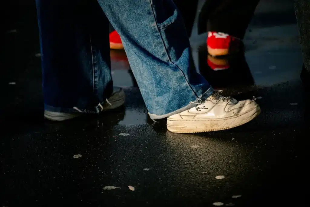 Person wearing wide-leg flared jeans on a city street, showing the leg-lengthening silhouette and movement of the fabric