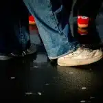 Person wearing wide-leg flared jeans on a city street, showing the leg-lengthening silhouette and movement of the fabric