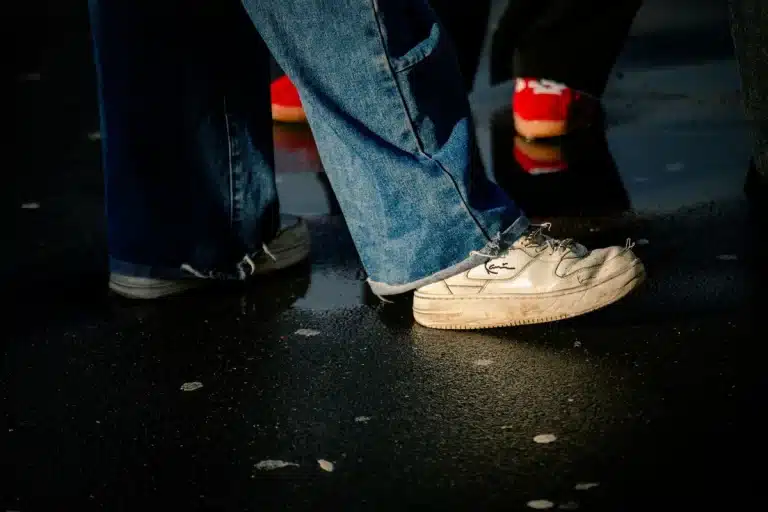 Person wearing wide-leg flared jeans on a city street, showing the leg-lengthening silhouette and movement of the fabric