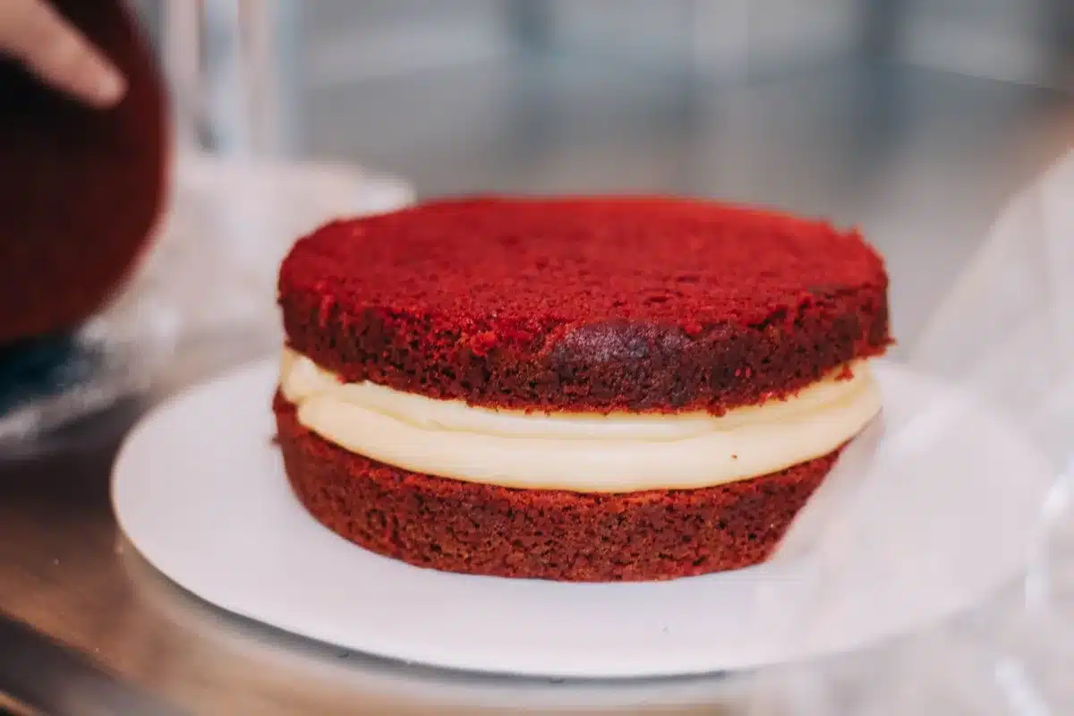 Spreading creamy lemon cheesecake layer over graham cracker crust in a baking dish