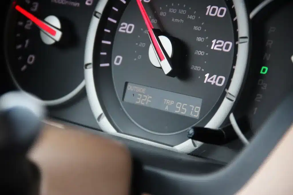 Close-up of hands on steering wheel with dashboard mileage counter visible