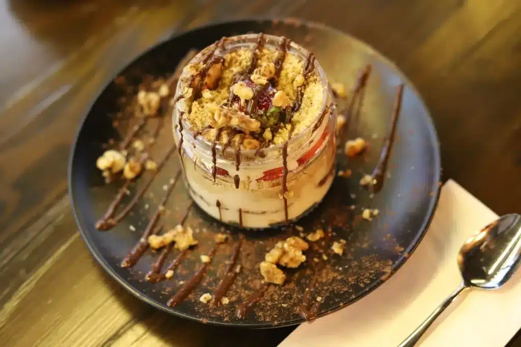 Hands carefully assembling layers of a multi-tiered cheesecake with chocolate and white cream on a pastry board