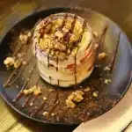 Hands carefully assembling layers of a multi-tiered cheesecake with chocolate and white cream on a pastry board