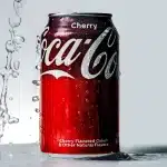 Magnifying glass examining nutrition label on soda can, revealing small print and ingredients