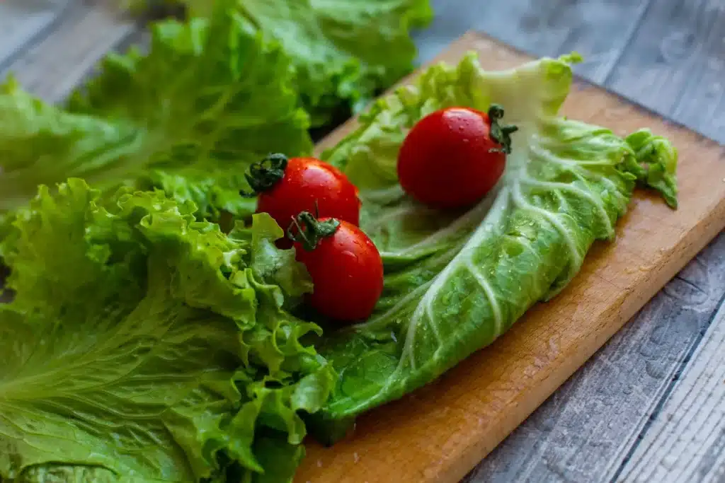 Fresh British vegetables including peppers, tomatoes and cucumber arranged on a kitchen counter with a salad box