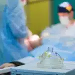 Medical professionals in hospital corridor near surgical suite with equipment