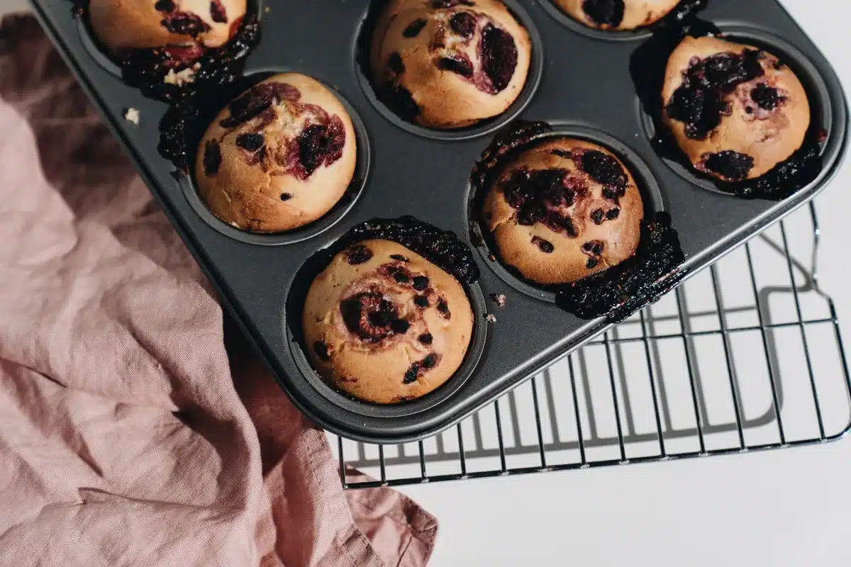Freshly baked strawberry muffins cooling on a wire rack with golden tops