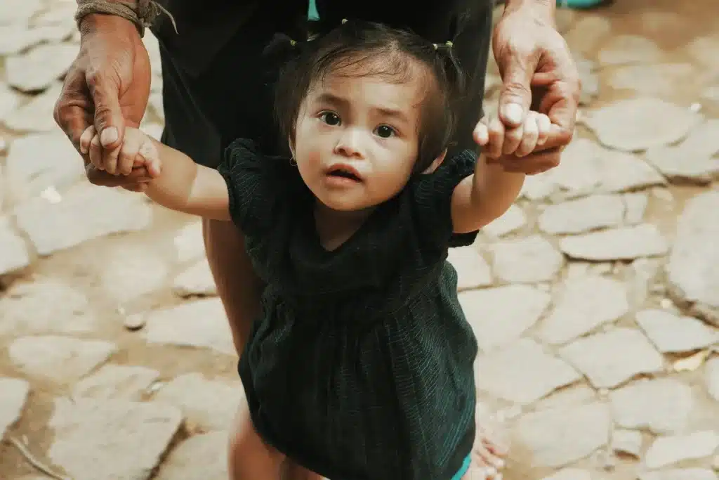 Young child taking first steps with support during physical therapy session