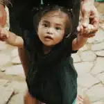 Young child taking first steps with support during physical therapy session