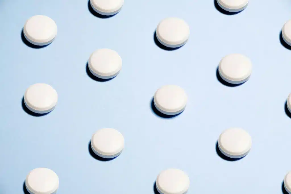 Blister pack of pain relief tablets next to a glass of water on a medical desk