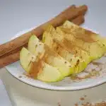 Pot of simmering apple cider with cinnamon sticks and orange slices on a kitchen counter