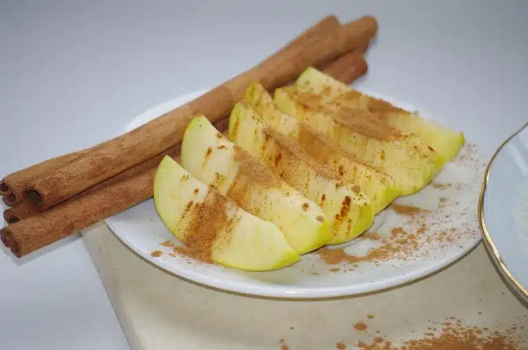 Pot of simmering apple cider with cinnamon sticks and orange slices on a kitchen counter