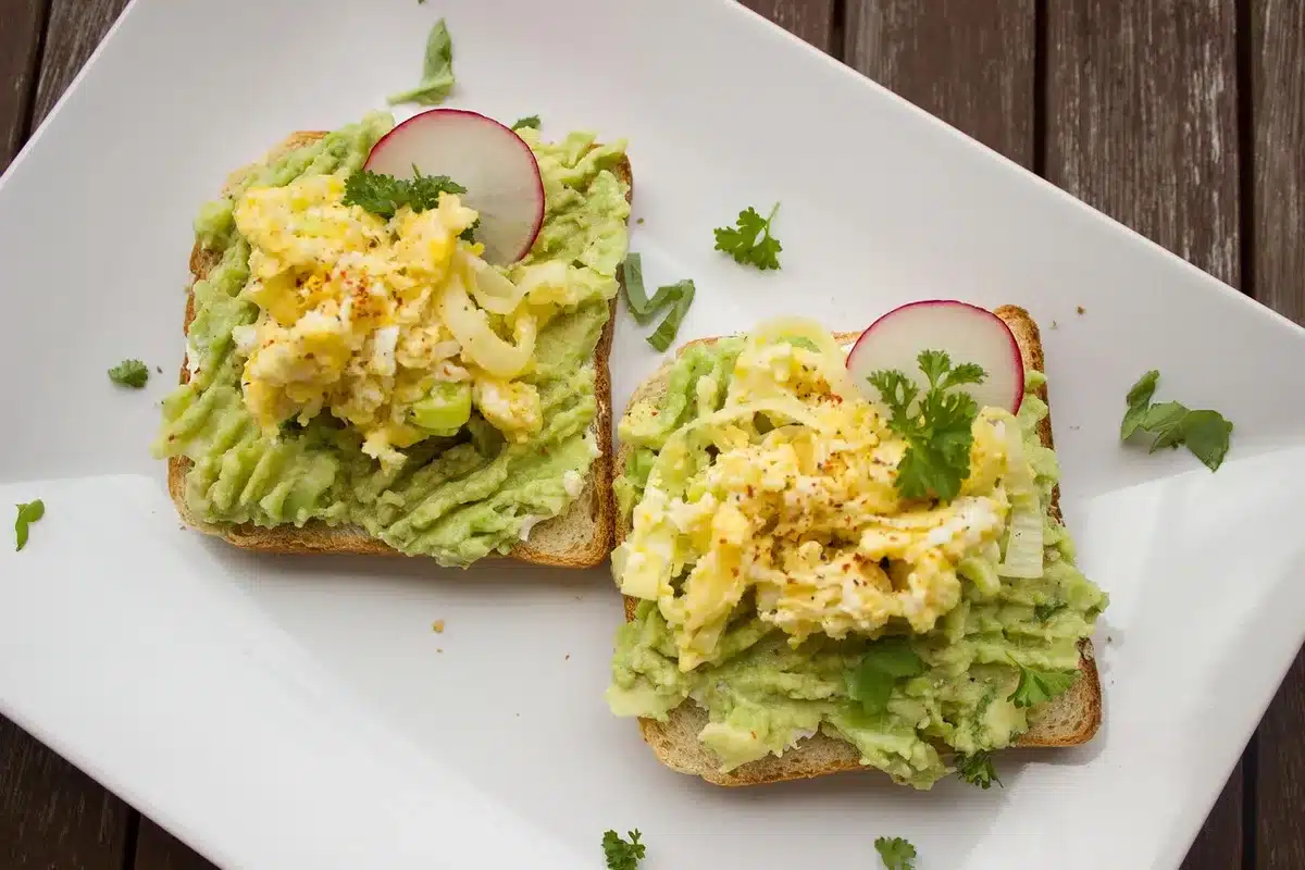 Mashed avocado spread on whole-grain toast with fresh toppings