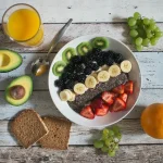 Ripe avocado halves on a plate with fresh vegetables and whole grains
