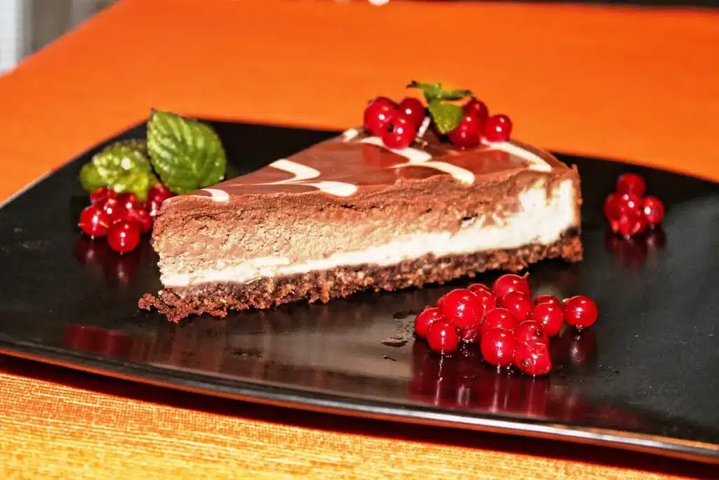 Sliced blueberry cheesecake bars on a plate with fork, showing layered crust, cream filling and berries