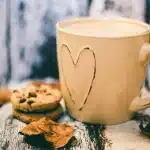 Anonymous hand filling a golden cookie cup in a muffin tin with chocolate-hazelnut spread
