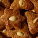 Zimtsterne cinnamon star cookies with powdered sugar, almonds and cinnamon sticks on a wooden surface