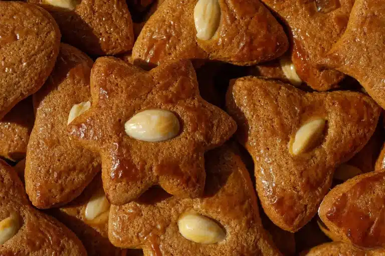Zimtsterne cinnamon star cookies with powdered sugar, almonds and cinnamon sticks on a wooden surface