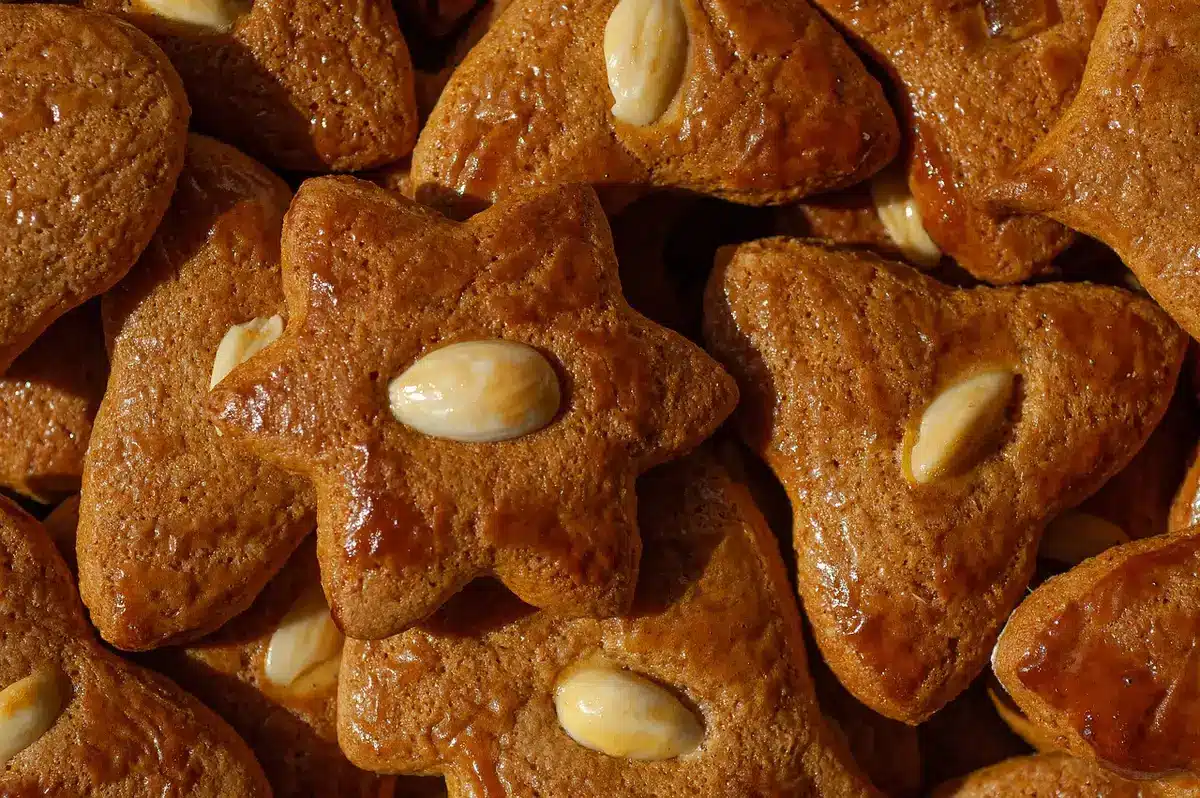 Zimtsterne cinnamon star cookies with powdered sugar, almonds and cinnamon sticks on a wooden surface