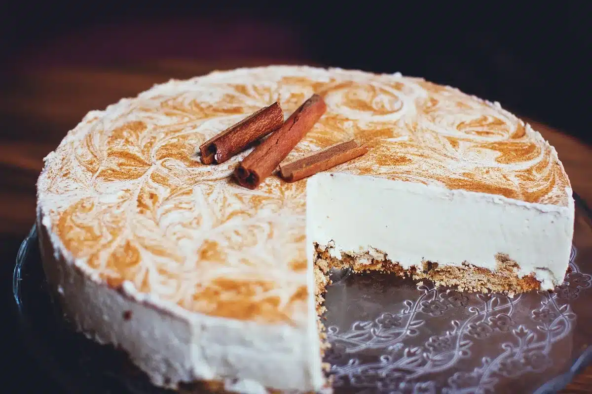 Hands spreading colorful pastel cheesecake layers into a rectangular baking dish