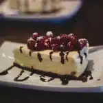 Layered pastel cheesecake lasagna with purple, blue, and yellow layers topped with whipped cream and Easter sprinkles
