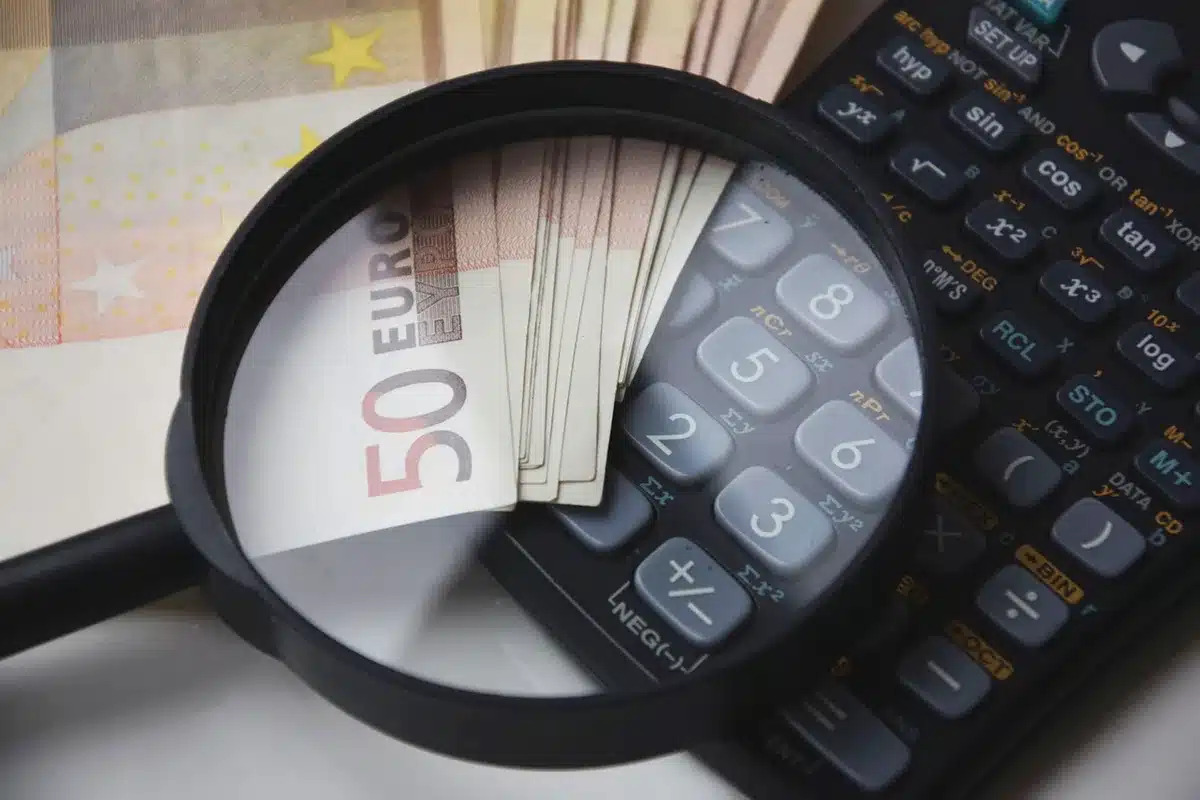 Hands filling an application form beside a calculator on a sunlit desk