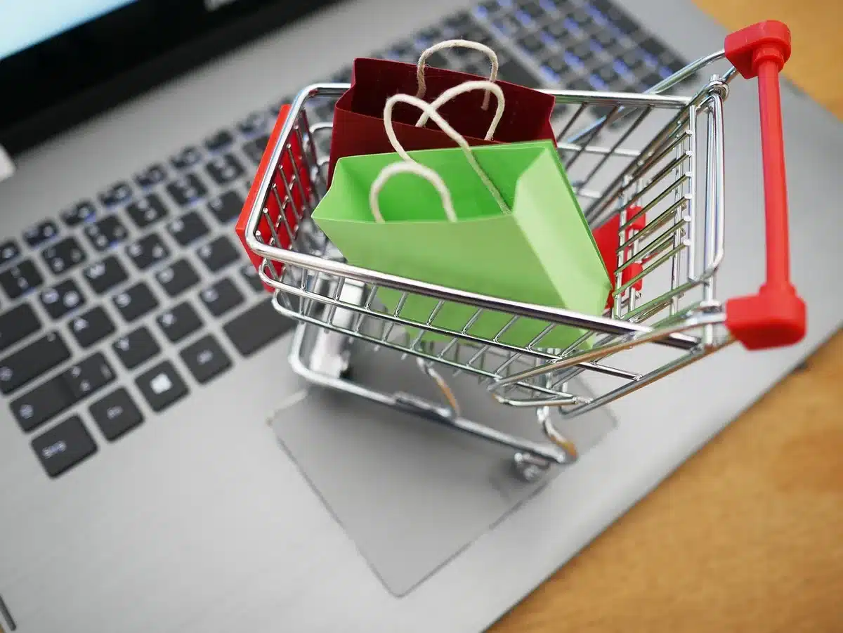 Person using a laptop at a kitchen table entering a promo code on an online checkout page