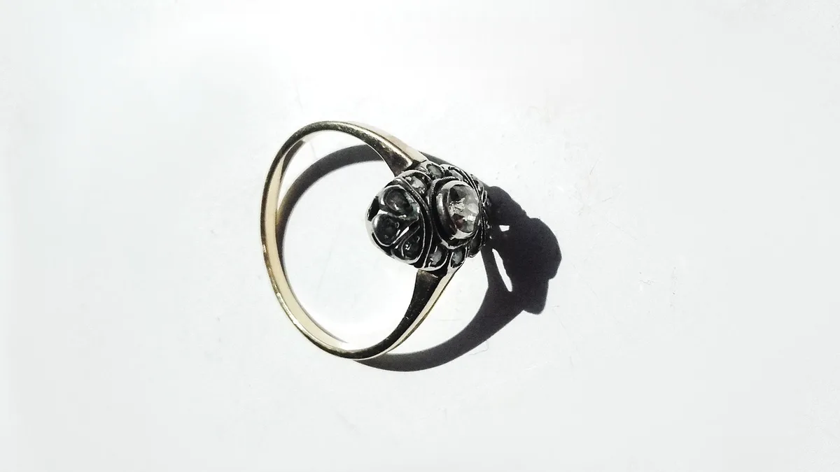 Close-up of a diamond and emerald set side-by-side on a simple band