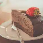 Une galette des rois dorée tranchée sur une assiette blanche avec une couronne en papier