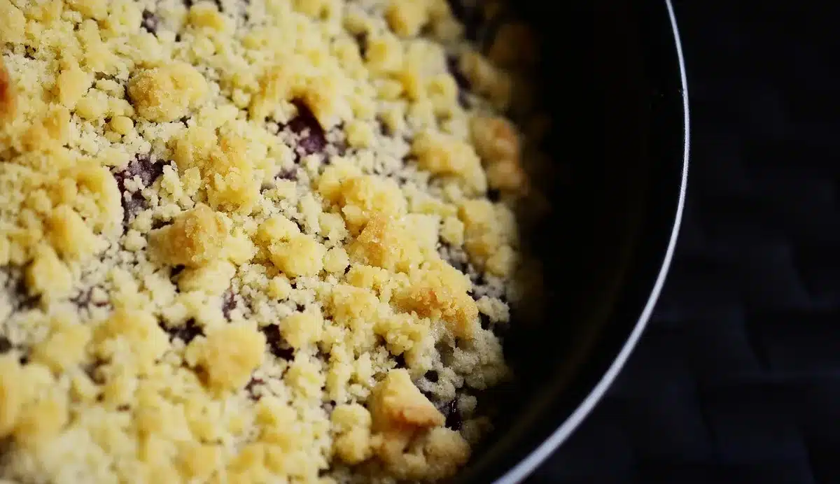 Hands breaking cooled red velvet cake into fine crumbs in a bowl