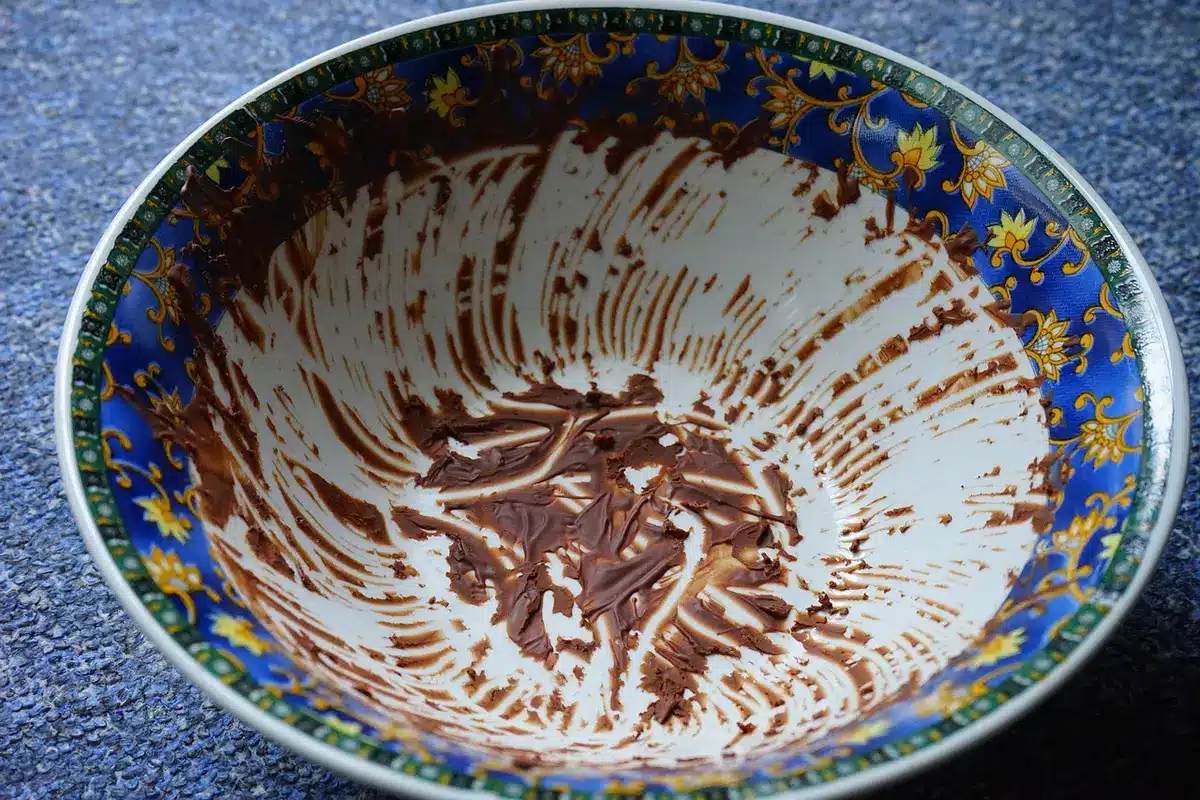Mixing graham cracker crumbs with melted butter in a bowl