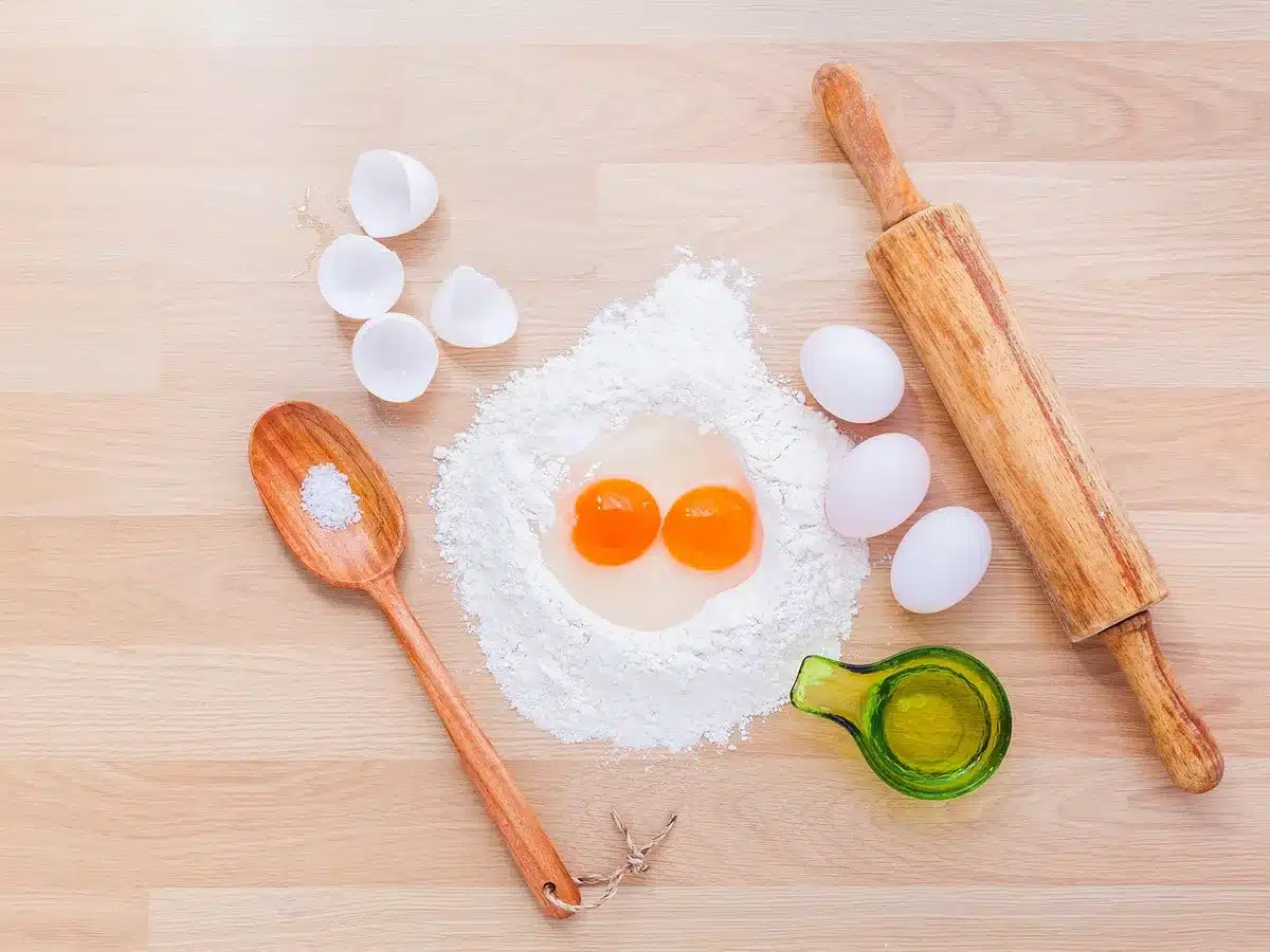 Baking ingredients laid out: fresh strawberries, flour, eggs, sugar, and yogurt