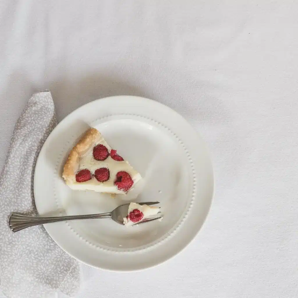 Summer berry sheet cake topped with cream cheese frosting and fresh raspberries and blueberries on a white plate