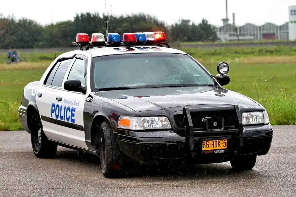 Police officers conducting a vehicle stop on a motorway hard shoulder with multiple high-performance cars lined up