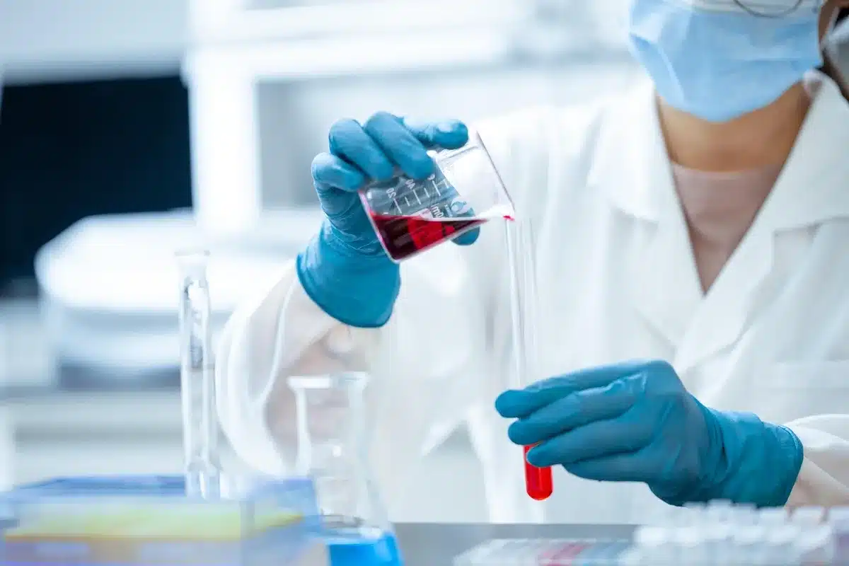 Laboratory technician handling a blood sample next to sequencing equipment