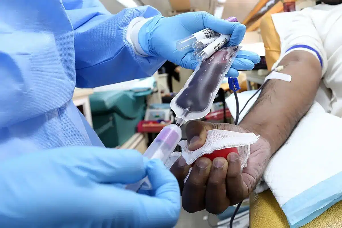 Gloved clinician visually inspecting an IV bag before use