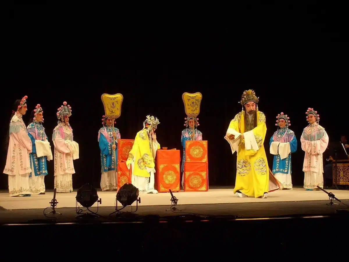 Three actresses rehearsing on a bright stage wearing theatrical costumes
